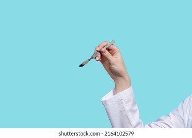 Close Up Faceless Female Surgeon Holding Metal Non-sterile Surgical Instrument. Doctor Shows Position Of Scalpel Like Writing Pen. Tutorial