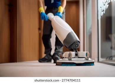 Close up of facility maintenance worker using professional floor cleaning machine.