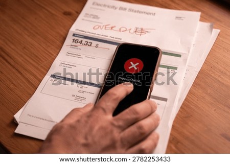Close up of failed payment message on smartphone over overdue utility bill on table. Concept of financial problem, declined transaction, online banking error and unpaid expenses.