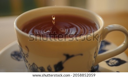 Close up of Falling drop into tea cup slow motion