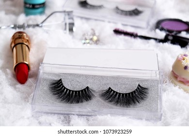 Close up of false eyelashes with make up tool and accessories with white fur background 