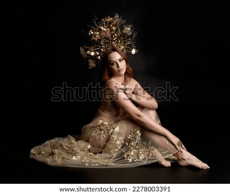 Close up fantasy portrait of beautiful woman model with red hair, goddess silk robes  ornate gold crown.  Posing with gestural hands reaching out, isolated on dark  studio background 