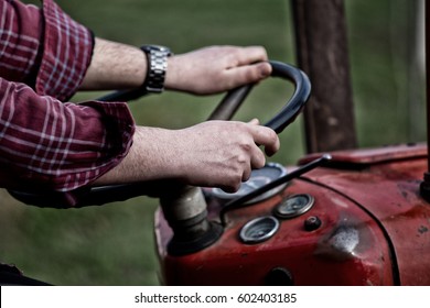 Close up of farmer's hands in plaid shirt on steering wheel of tractor. Farming concept - Powered by Shutterstock