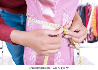 Close up of fashion designer measuring waist - Powered by Shutterstock