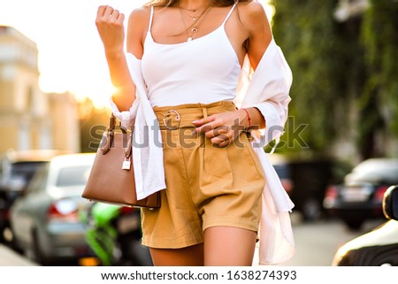 Close up fashion details of stylish woman posing the street wearing trendy casual fashionable outfit, beige short, white tip and caramel luxury leather bag, street style, vacation mood.