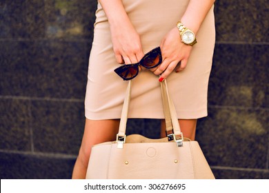 Close up fashion details, young business woman holding bag and retro sunglasses, golden jewelry, warm colors. - Powered by Shutterstock