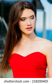 Close up fashion portrait of beautiful woman with long dark hair  in an elegant long red dress.