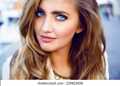 Close up fashion portrait of seductive sexy woman with big blue eyes ,full lips , prefect skin and long fluffy curled hairstyle. Natural make up.