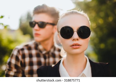 Close up fashion portrait of young couple posing on the city street in summer style clothes, retro sunglasses,fashionable couple in sunglasses,trendy outfits,autumn clothes,sunglasses fashion,black 
