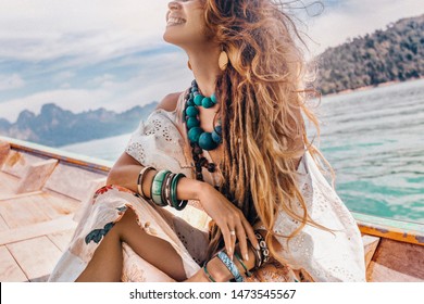 close up of fashionable young model in boho style dress on boat at the lake 