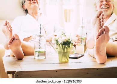 close up of feet of couple of seniors on the tale in a resort hotel or at home with a cocktail or drink - healthy and great lifestyle - enjoying together sitted at home - Powered by Shutterstock