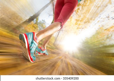 Close Up Of Feet Of Female Runner Running In Autumn Leaves. Fitness Exercise. Blur Motion