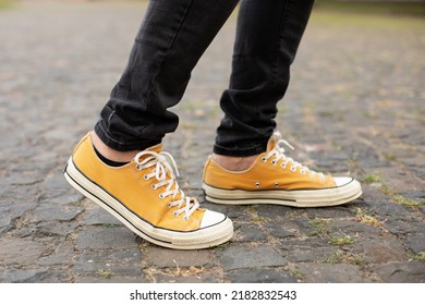 Close Up Feet Of Man While Walking Commuting To Work. Male In Yellow Sneakers Being Walking Down The Street. Confident Man Feet Walking In City. Man Legs In In Shoes Walking On Sidewalk. 