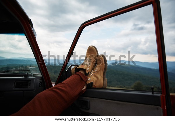 Close up of feet of a relaxed\
traveler holding them on the window while enjoying mountains\
view