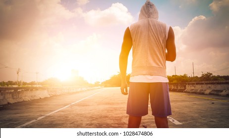 close up feet with running shoes and strong athletic legs of sport man, Athlete man in running pose on city street. Sport tight clothes. Bright sunset - Powered by Shutterstock