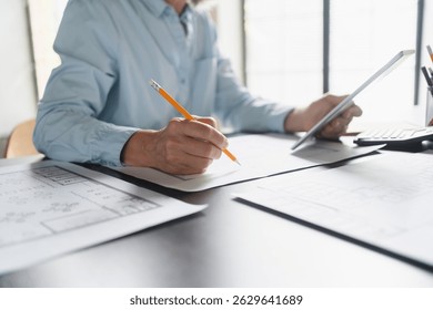 Close up of female Architect hands mature Caucasian business woman working with blueprints for architectural plan, engineer sketching a construction project, green energy concept