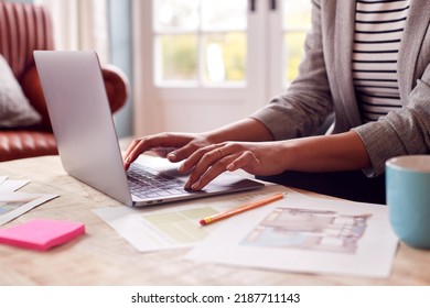 Close Up Of Female Architect Or Interior Designer Working From Home Looking At Designs On Laptop