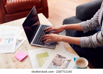 Close Up Of Female Architect Or Interior Designer Working From Home Looking At Designs On Laptop