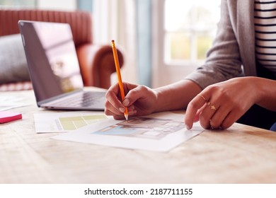 Close Up Of Female Architect Or Interior Designer Working From Home Looking At Designs On Laptop