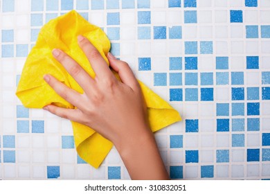 Close Up Of Female Arm Of Cleaner Washing Tile On Wall In Bathroom With Yellow Washcloth