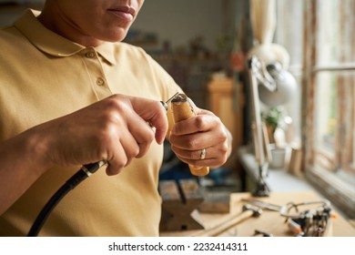 Close up of female artist creating handmade jewelry with wooden tools in cozy workshop lit by sunlight, copy space - Powered by Shutterstock