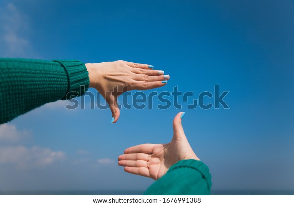 Close up of female caucasian hands isolated at\
blue sea and sky background. Young woman forms frame with her two\
hands as if looking at something virtual and invisible in distance.\
Point of view shot.
