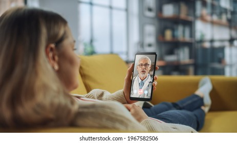 Close Up of a Female Chatting in a Video Call with Her Senior Family Doctor on Smartphone from Living Room. Ill-Feeling Woman Making a Call from Home with Physician Over the Internet. - Powered by Shutterstock