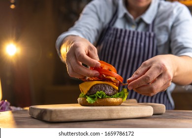 Close up of a female chef, preparing a tasty, fresh, delicious hamburger in a restaurant or pub - Powered by Shutterstock