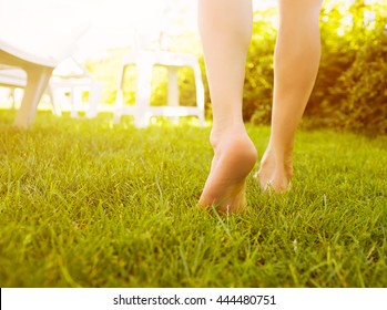 Close up female crossed legs walking on the grass in a park.