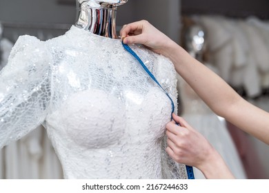 Close Up Of Female Designer Dressmaker Hand Fitting Bridal Dress With Measure Tape In  Boutique