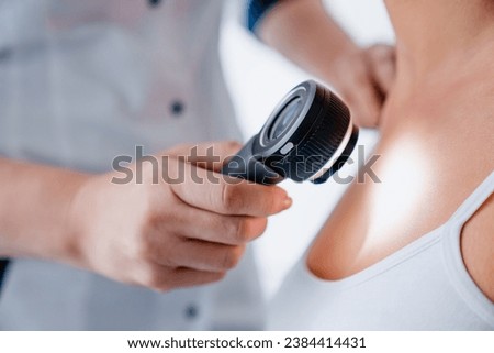 Close up of female doctor checking skin of girl with dermatoscope in clinic. Dermatologist checkup. Skinhealth concept. Skin cancer, melanoma prevention