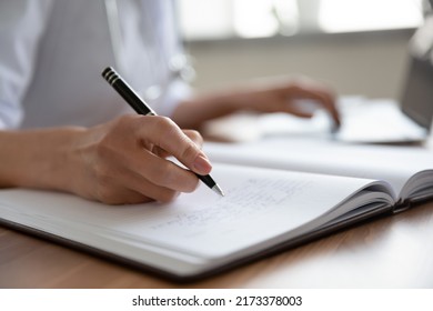 Close up female doctor filling documents and using laptop, sitting at work desk in hospital, young woman physician therapist practitioner gp writing illness history, prescription in patient card - Powered by Shutterstock