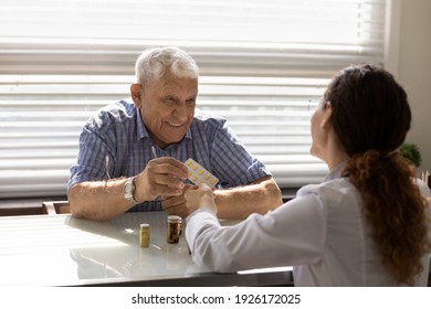 Close up female doctor giving prescribing medicine to smiling senior man at meeting in hospital, physician explaining treatment, pharmacist holding blister pack of pills, vitamins, healthcare concept - Powered by Shutterstock