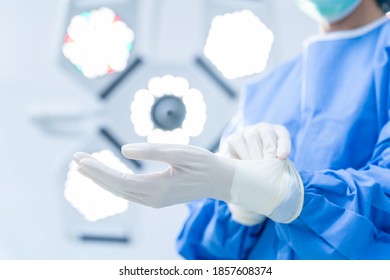 Close Up Of Female Doctor Hands With Surgical Gloves In The Operating Room. Medical Staff Protective Gear Against Coronavirus COVID 19. Health Care, Hospital Safety Concept.