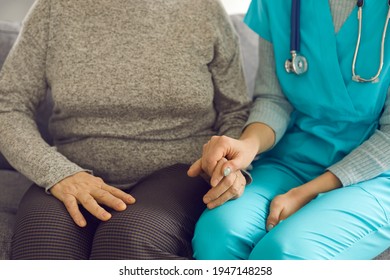 Close Up Of A Female Doctor Or Nurse Holding The Hand Of Her Elderly Patient As A Sign Of Care And Support. Nurse Comforts The Older Woman During A Medical Visit Home. Concept Of Helping The Elderly.