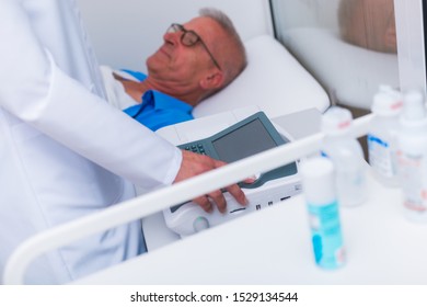 Close Up Of A Female (doctor) Nurse Performs An EKG Test On An Older Man.