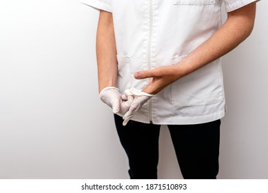 Close Up Of A Female Doctor Taking Off White Latex Gloves On A Clinic Background.