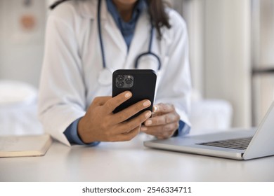 Close up female doctor using smartphone at workplace, access records, review medical histories, conduct virtual consultations with patients, provide advice, prescribe medication through telehealth app - Powered by Shutterstock