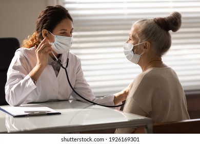 Close Up Female Doctor Wearing Face Mask Checking Mature Patient Lungs, Holding Using Stethoscope, Listening To Elderly Woman Breath, Sitting In Hospital Office, Medical Checkup And Healthcare