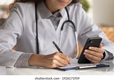 Close Up Female Doctor Wearing Uniform With Stethoscope Holding Smartphone, Taking Notes, Therapist Physician Writing Down Patient Complaints, Consulting Online, Filling Medical Form, Telemedicine