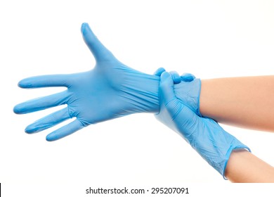 Close Up Of Female Doctor's Hands Putting On Blue Sterilized Surgical Gloves Against White Background