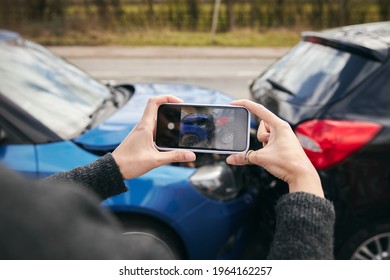 Close up of female driver taking photos of road traffic accident on mobile phone for insurance claim