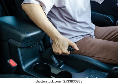 Close up of female driver's hand pulling hand brake lever. Handbrake in car.