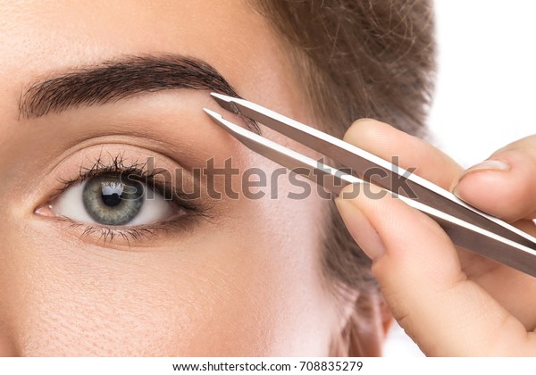 Close up of\
female face and eyebrow with\
tweezers