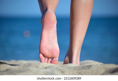 Close Up Of Female Feet Walking Barefoot On White Grainy Sand Of Golden Beach On Blue Ocean Water Background