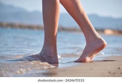 Close up of female feet walking barefoot on white grainy sand of golden beach on blue ocean water background - Powered by Shutterstock