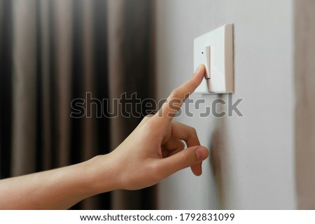 Close up of Female finger is turn off on lighting switch at home. Power, Energy, Saving Electrical, Copy space. 