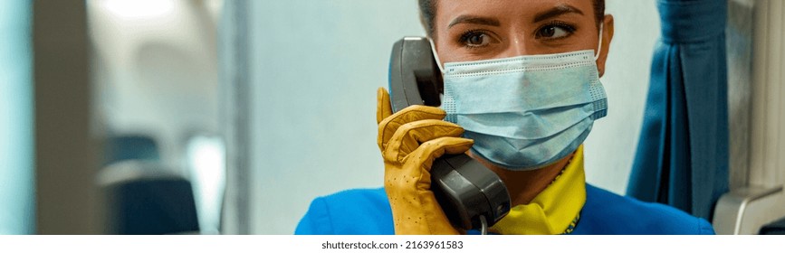 Close Up Of Female Flight Attendant In Protective Face Mask Having Phone Conversation In Aircraft Cabin