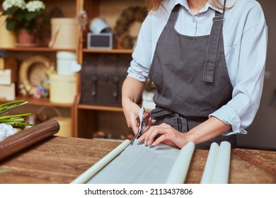 Close Up Of Female Florist Hands Cutting Color Wrapping Paper With Scissors For Freshly Made Bouquet In The Flower Shop