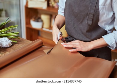 Close Up Of Female Florist Hands Cutting Color Wrapping Paper With Scissors For Freshly Made Bouquet In The Flower Shop